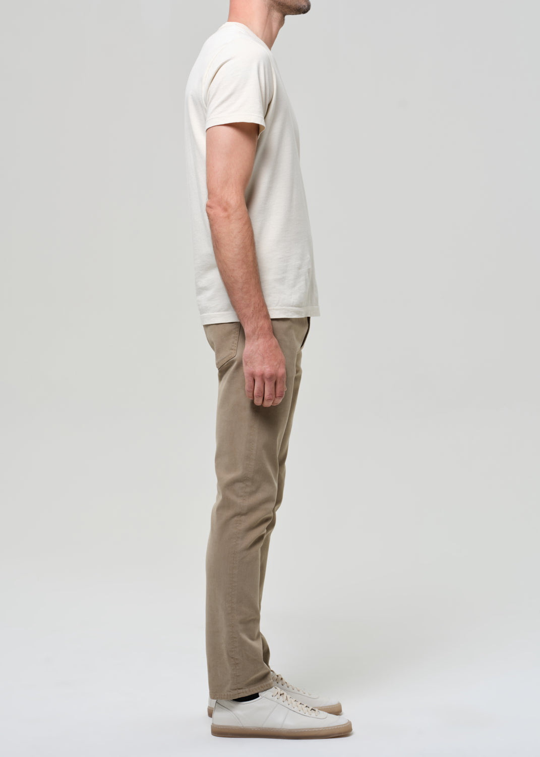 Person wearing a white t-shirt and beige pants on a plain background
