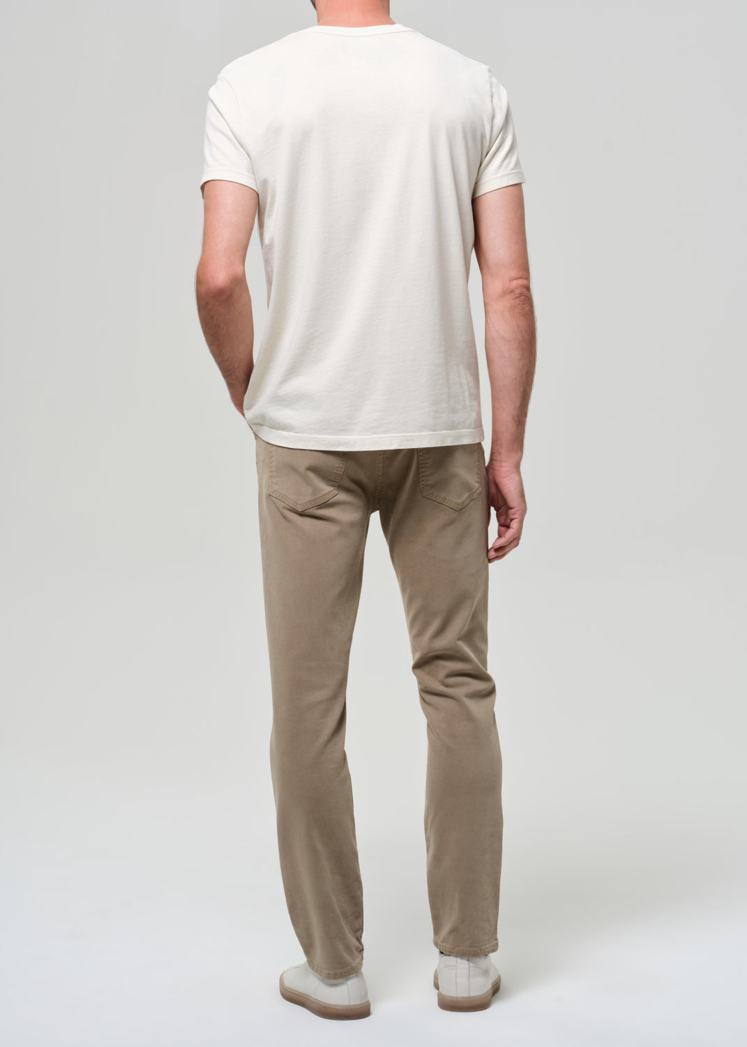 Person wearing a white t-shirt and beige pants on a plain background