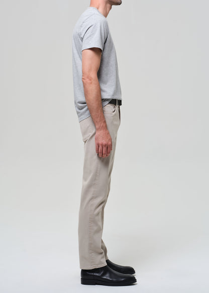 Person wearing a gray t-shirt, beige pants, and black shoes on a white background