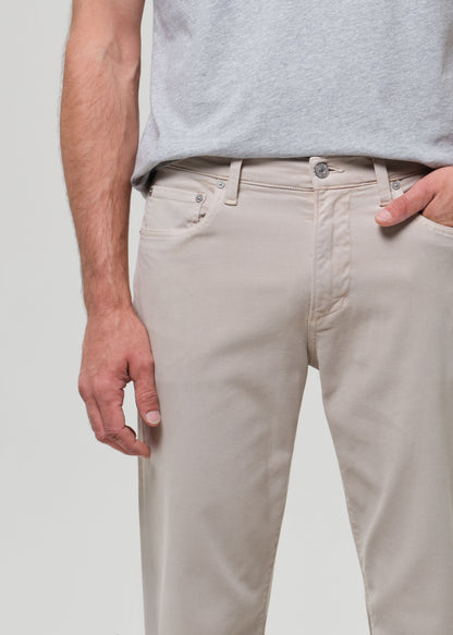 Person wearing beige pants and a gray shirt on a plain background