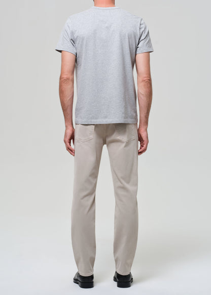 Person wearing a gray t-shirt and beige pants on a white background