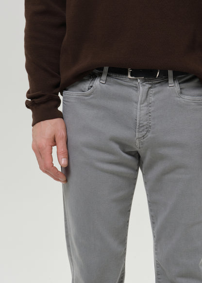 Person wearing grey pants and a brown sweater on a grey background