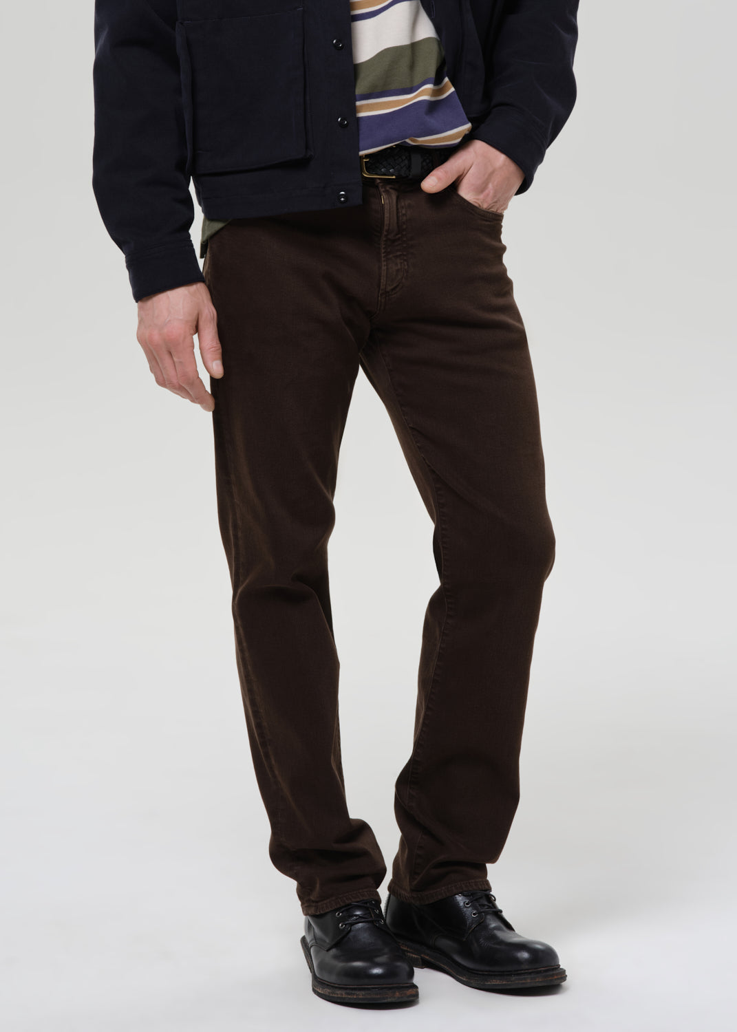 Person wearing brown pants and a dark jacket on a grey background