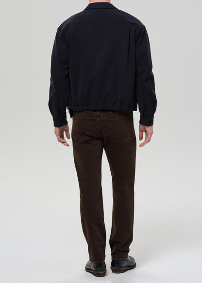 Person wearing a navy jacket and brown pants on a grey background