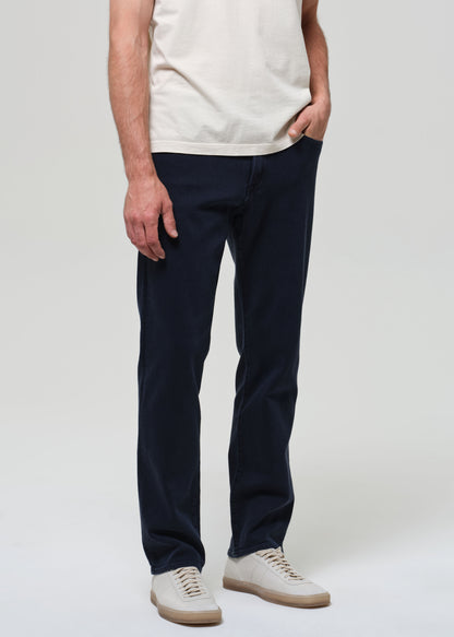 Person wearing navy pants and a white shirt on a plain background