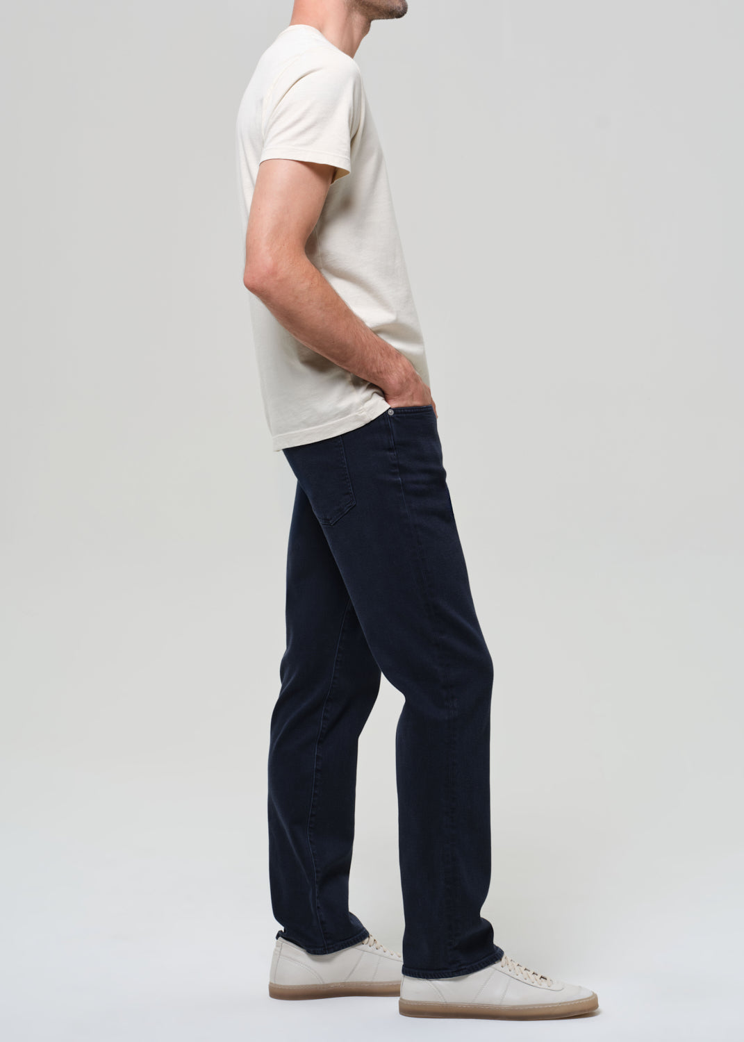 Person wearing a white t-shirt and dark pants on a plain background