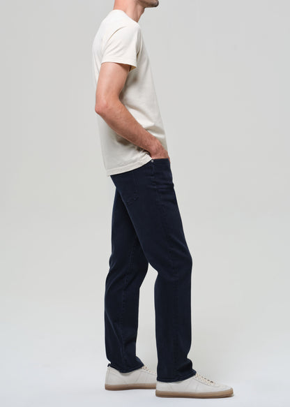 Person wearing a white t-shirt and dark pants on a plain background