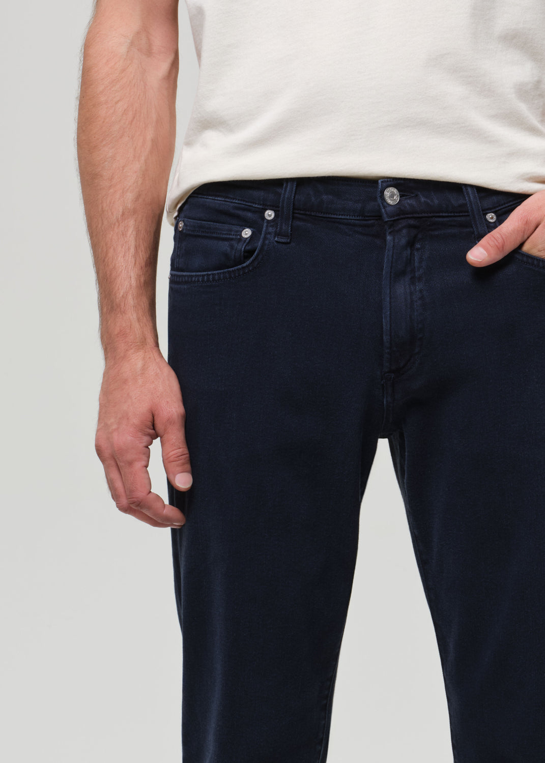 Navy blue jeans worn by a person on a light gray background