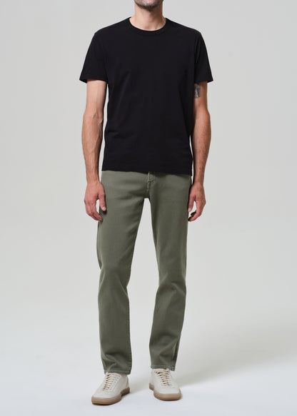 Person wearing a black t-shirt and green pants on a white background