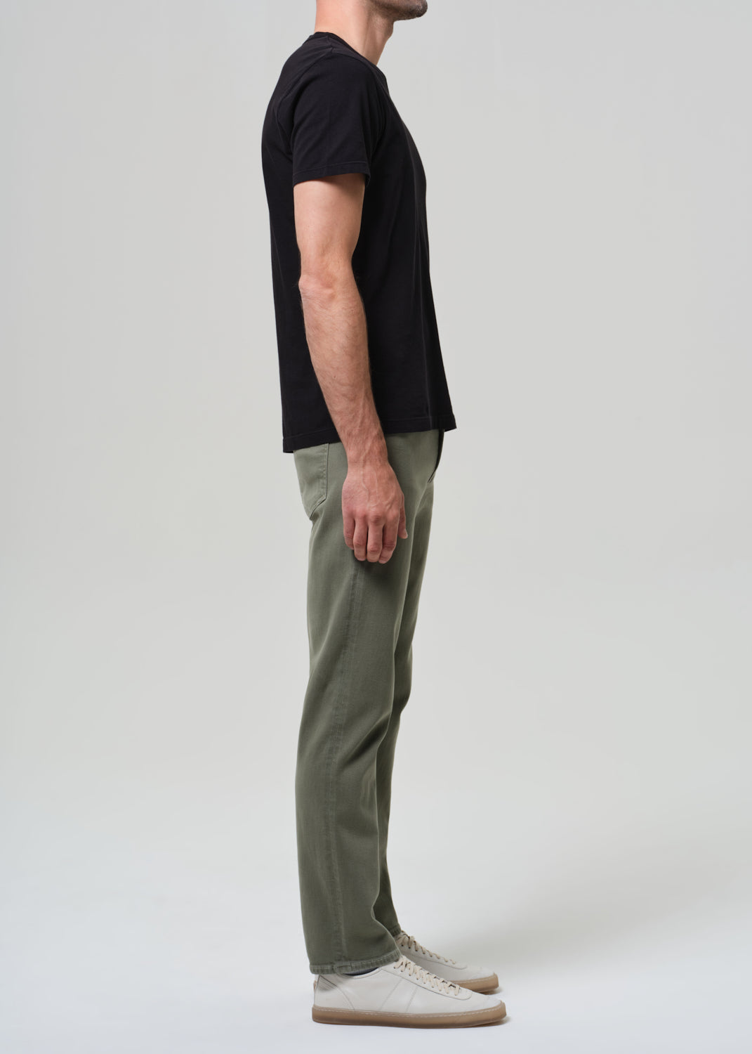 Person wearing a black t-shirt and green pants on a white background