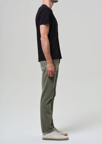 Person wearing a black t-shirt and green pants on a white background