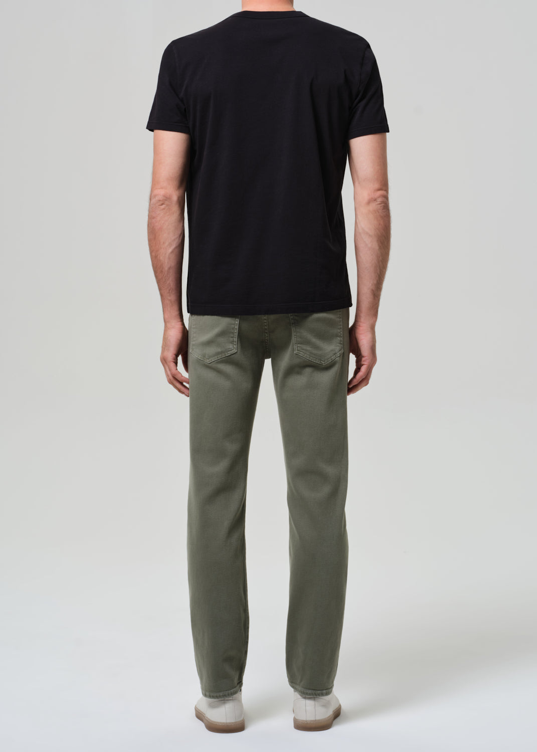 Person wearing a black t-shirt and green pants on a white background