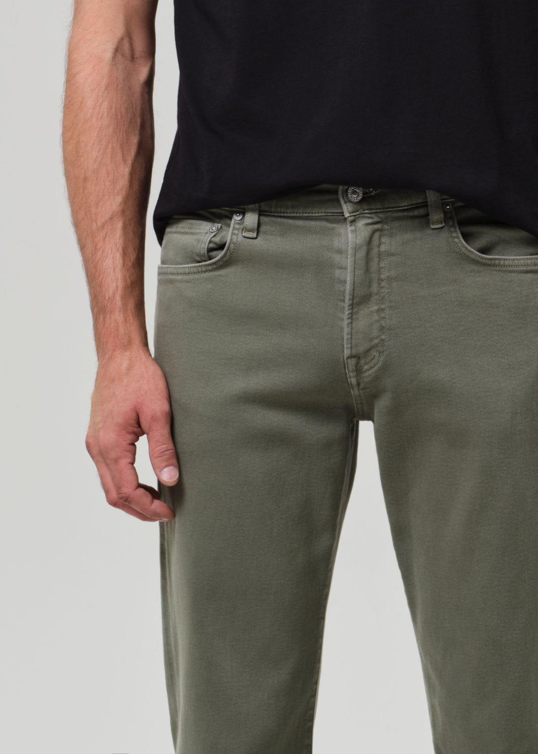 Person wearing olive green pants and a black shirt on a plain background