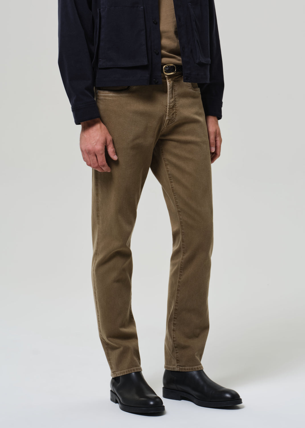 Person wearing brown pants and black shoes on a white background