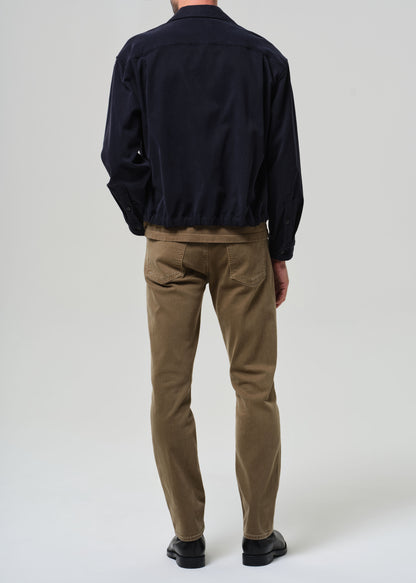 Person wearing a navy jacket and brown pants on a white background