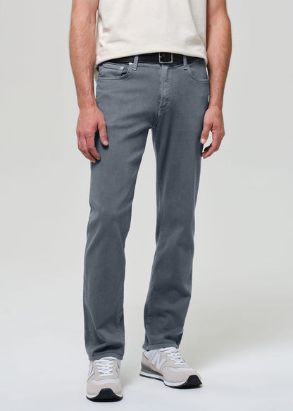 Person wearing a white shirt, grayish blue jeans, and sneakers on a plain background