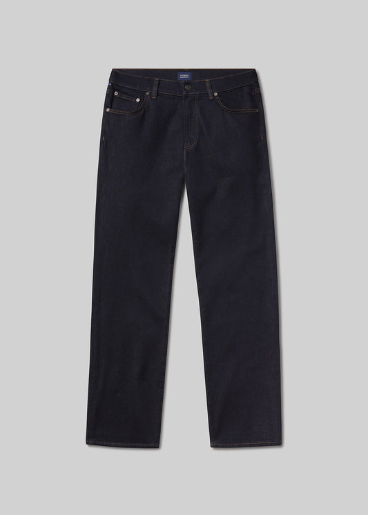 Flat lay of a pair of dark blue jeans on a light grey background