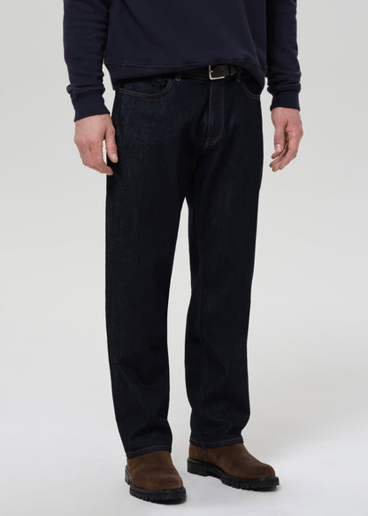 Person wearing dark blue jeans and a dark shirt on a grey background