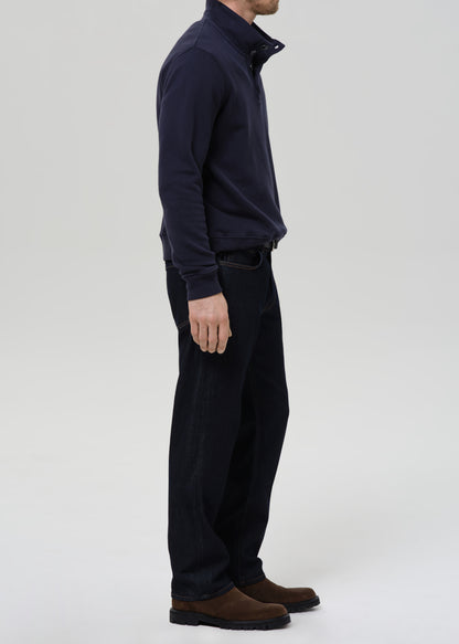 Person wearing a navy blue jacket and dark pants on a grey background