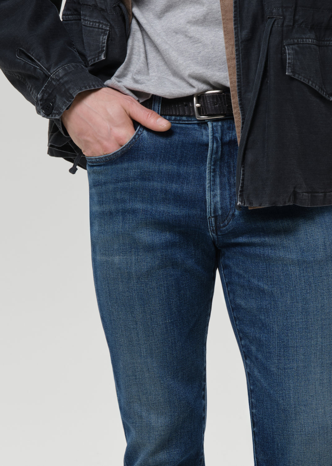 Person wearing blue jeans with a grey background