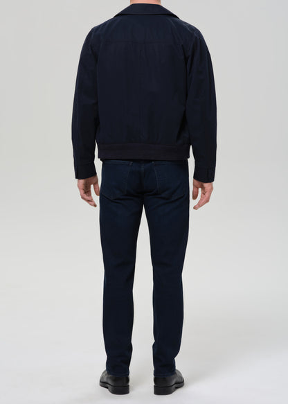 Person wearing a navy jacket and pants on a grey background