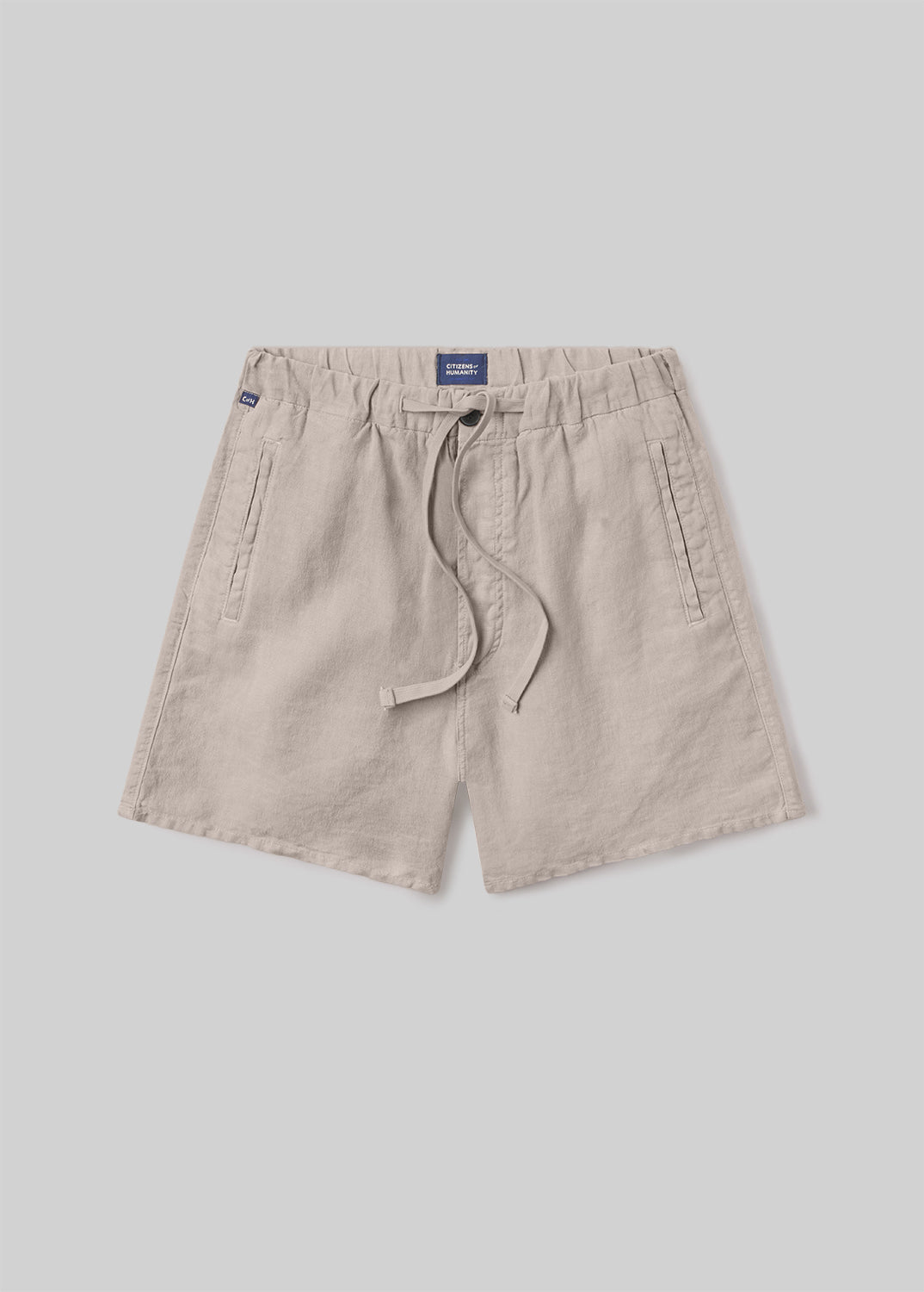 Beige drawstring shorts with an elastic waistband, adjustable drawstring, and side pockets, front flat lay view on a grey background.