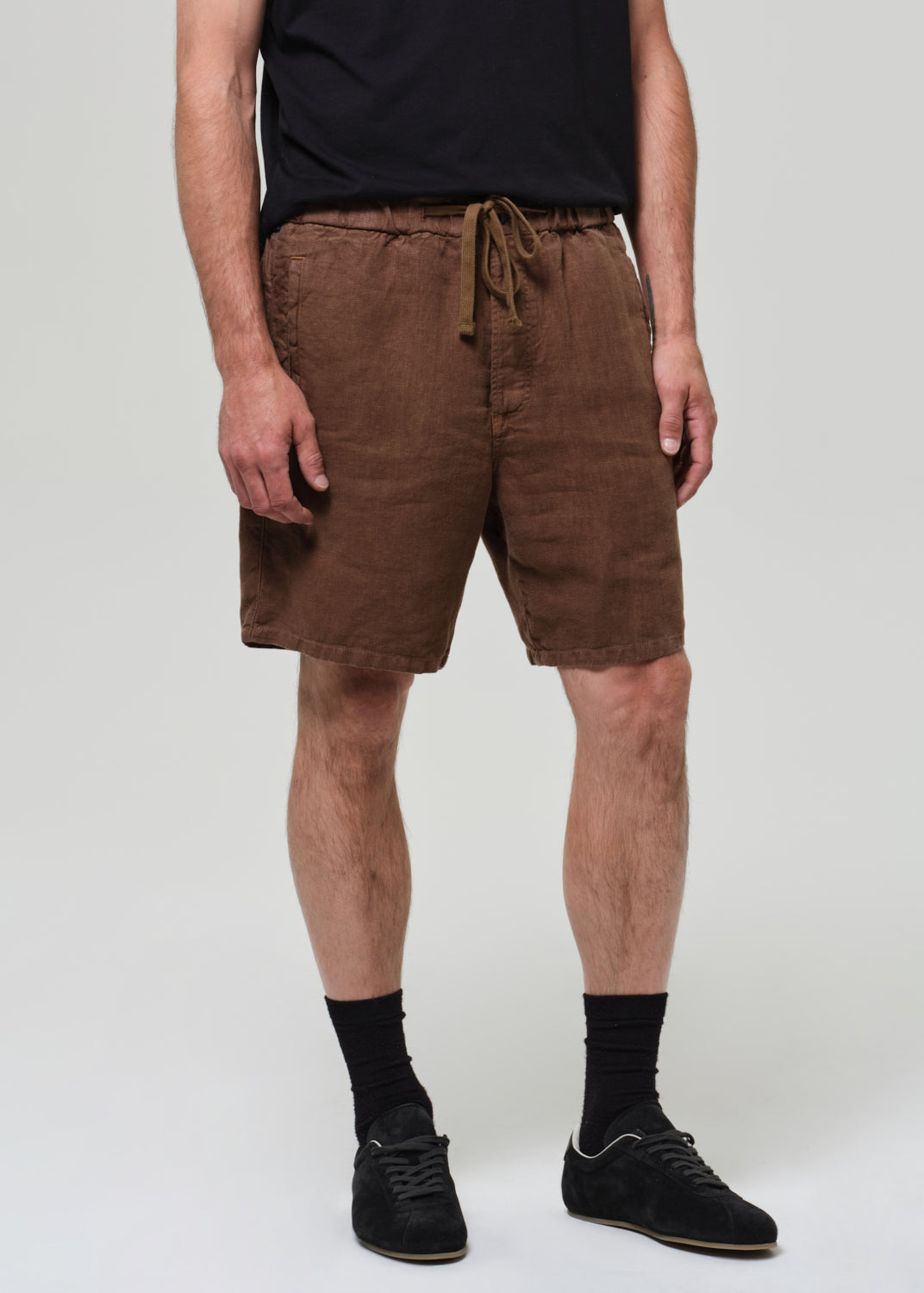 Person wearing brown shorts on a grey background