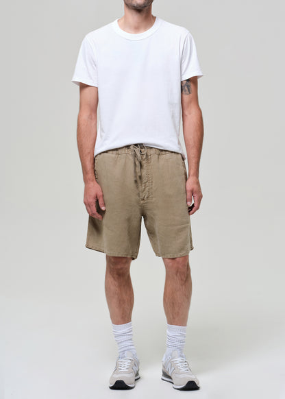 Person wearing a white t-shirt and beige linen shorts on a plain background