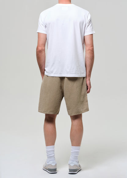Person wearing a white t-shirt and beige linen shorts on a plain background