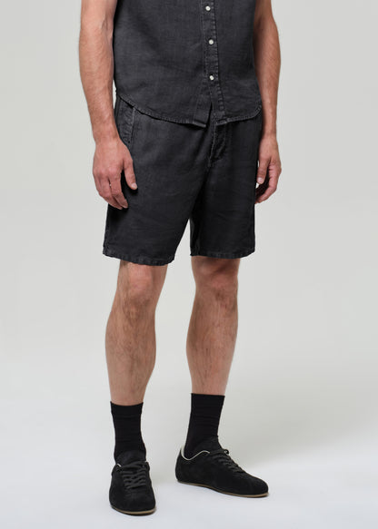 Person wearing a washed black button-up shirt and shorts on a plain background