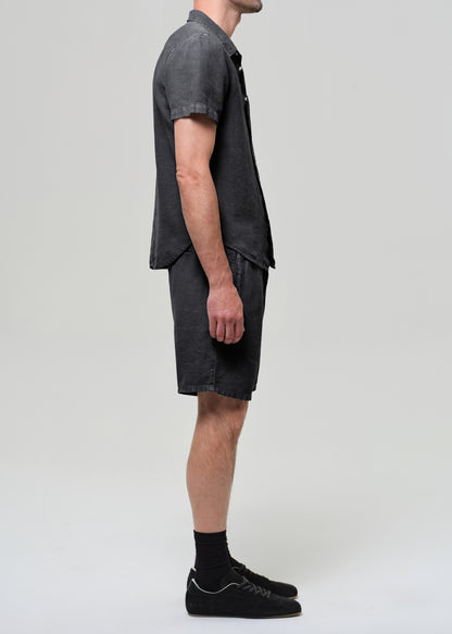 Person wearing a washed black button-up shirt and shorts on a plain background