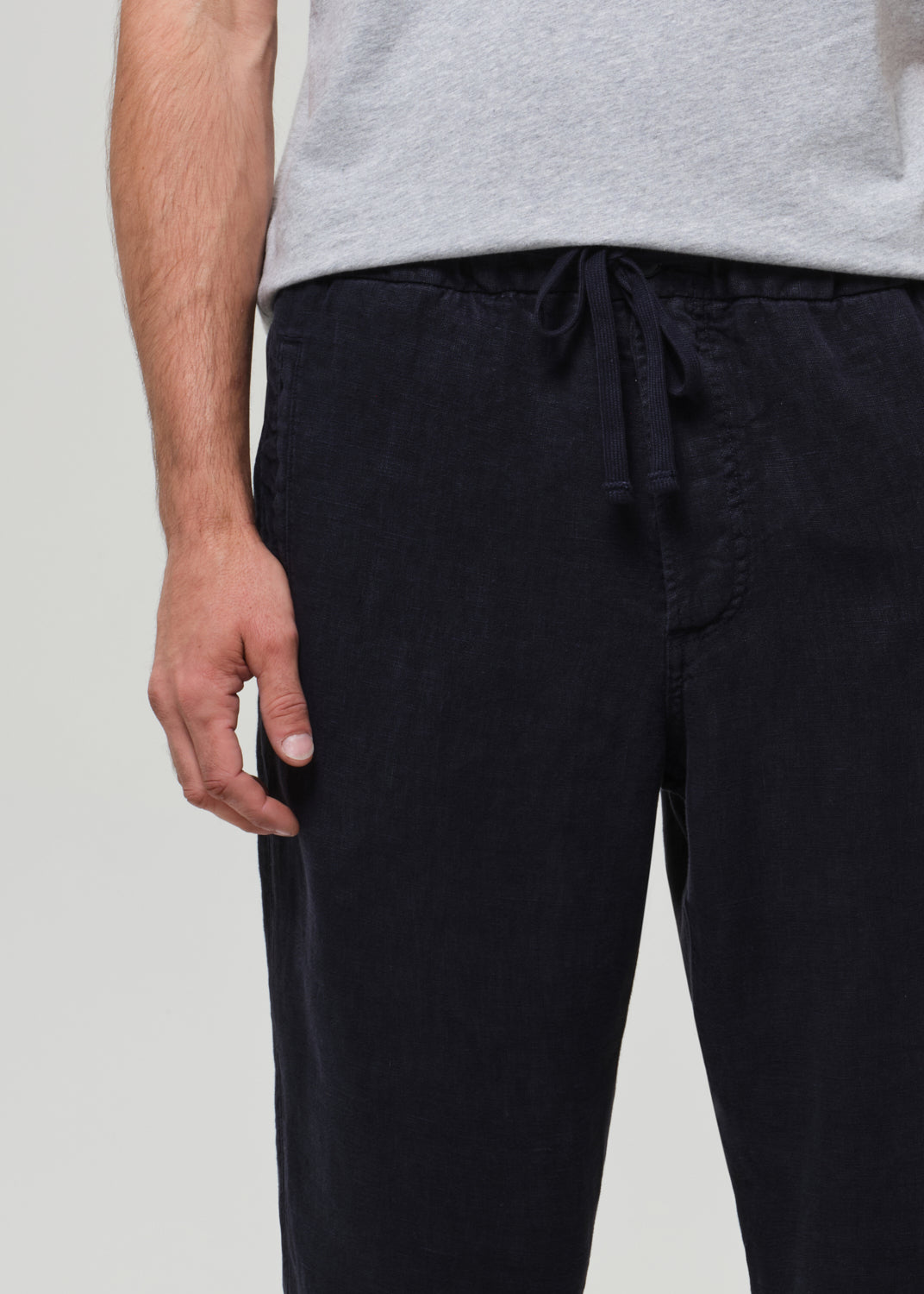 Person wearing navy pants and a gray shirt on a plain background