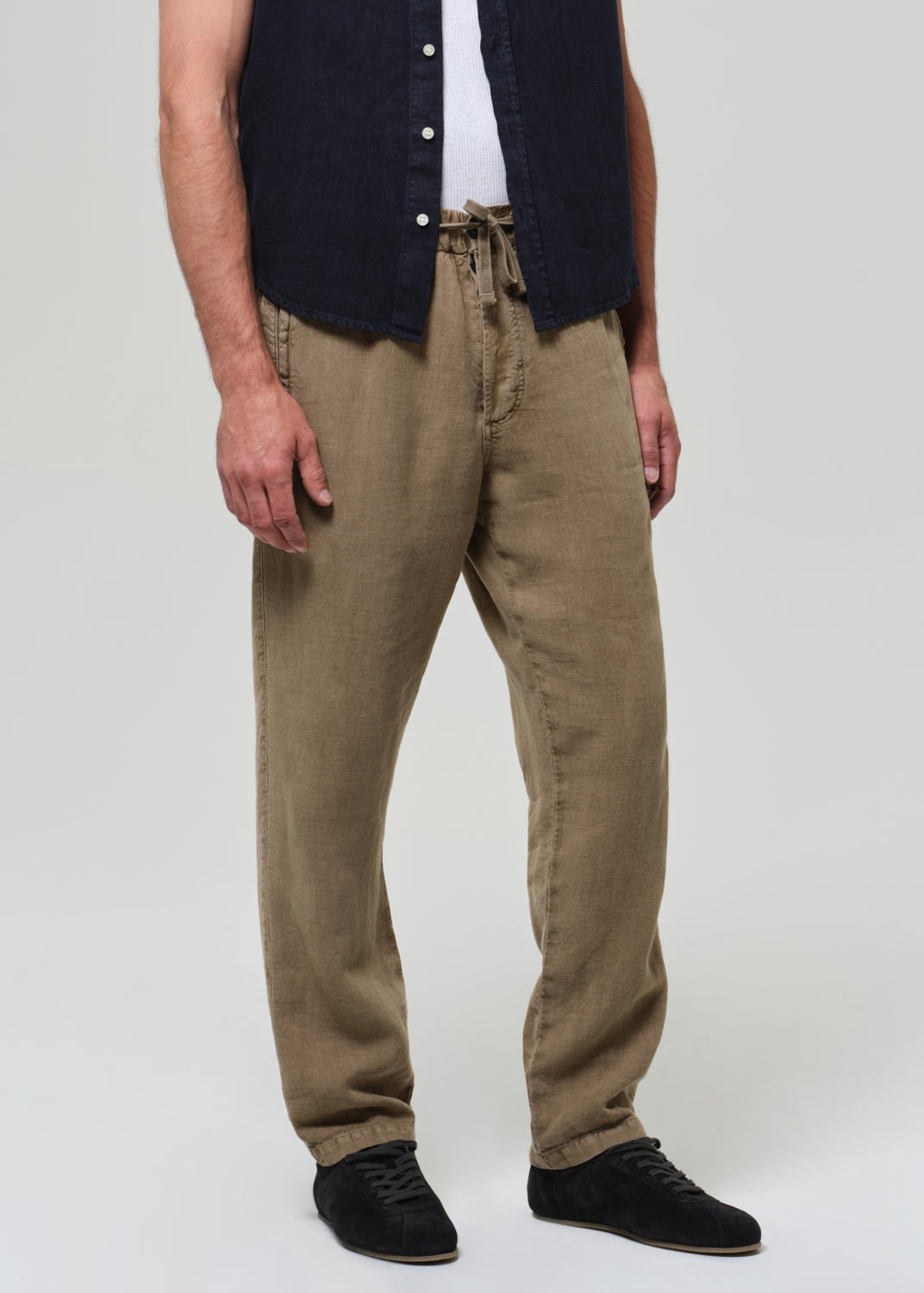 Person wearing beige pants and a navy shirt on a plain background