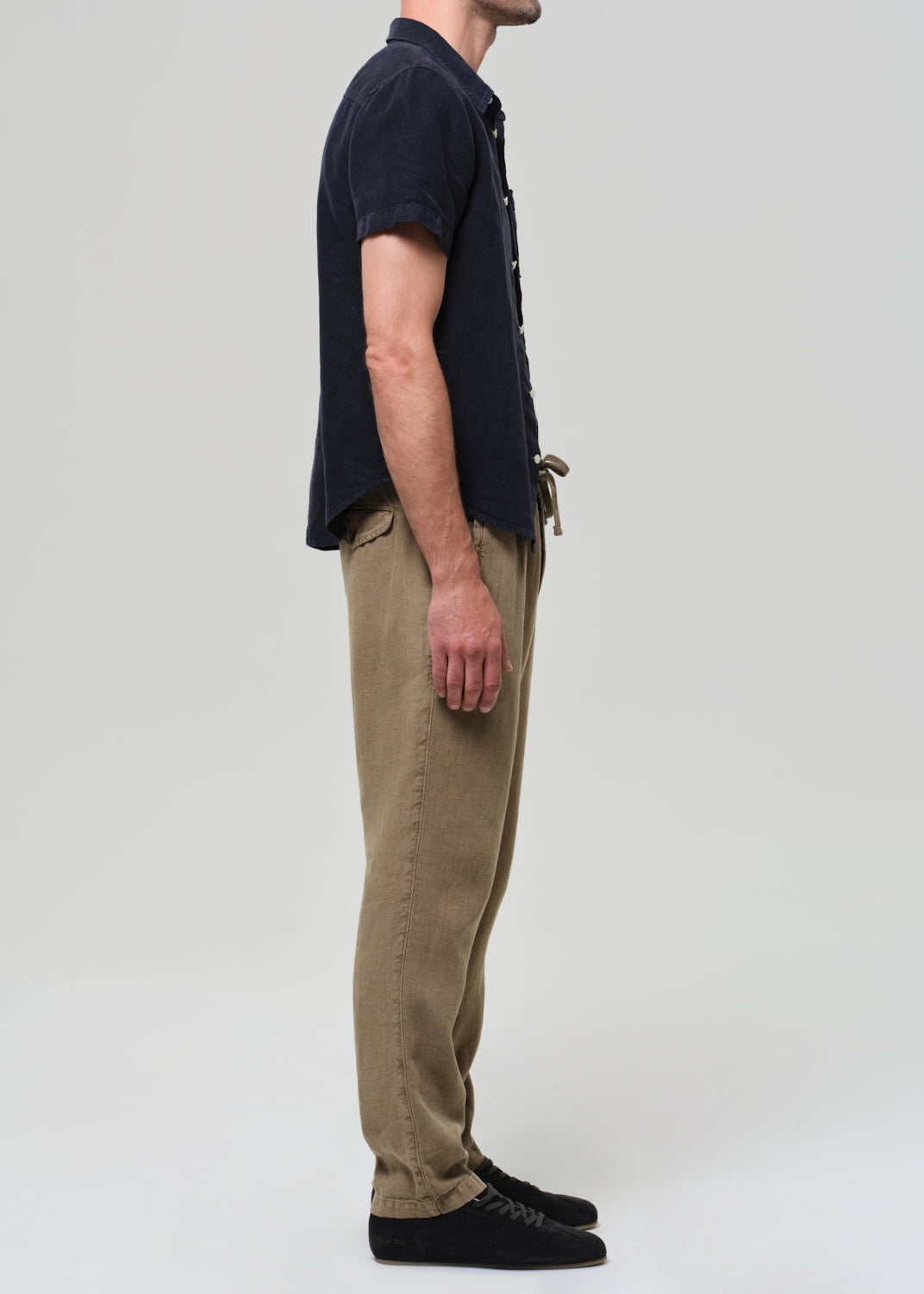 Person wearing a navy shirt and beige pants on a white background