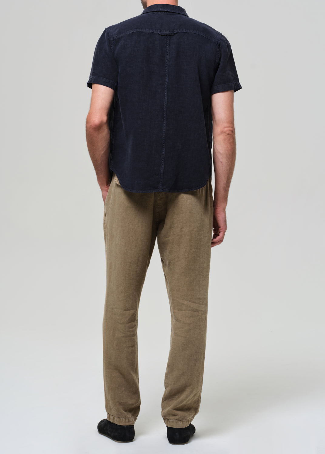 Person wearing a dark blue shirt and beige pants on a white background