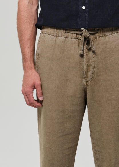 Person wearing beige pants with a plain background