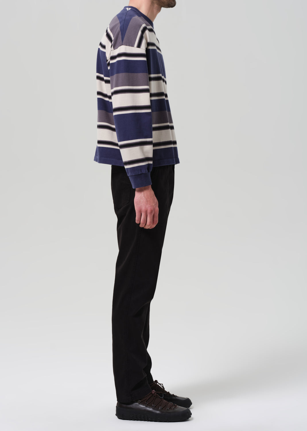 Person wearing a striped sweater and black pants on a plain background