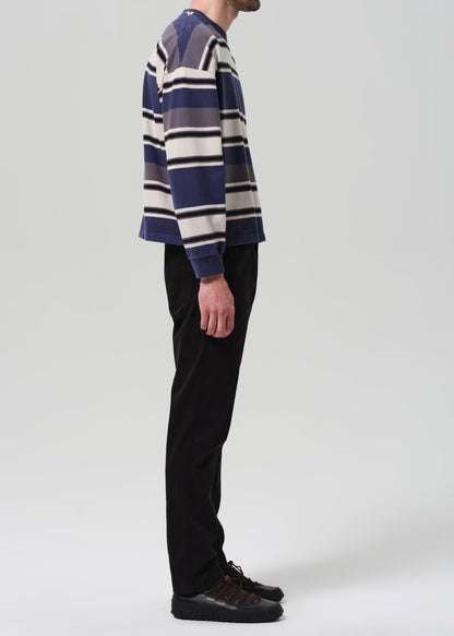 Person wearing a striped sweater and black pants on a plain background