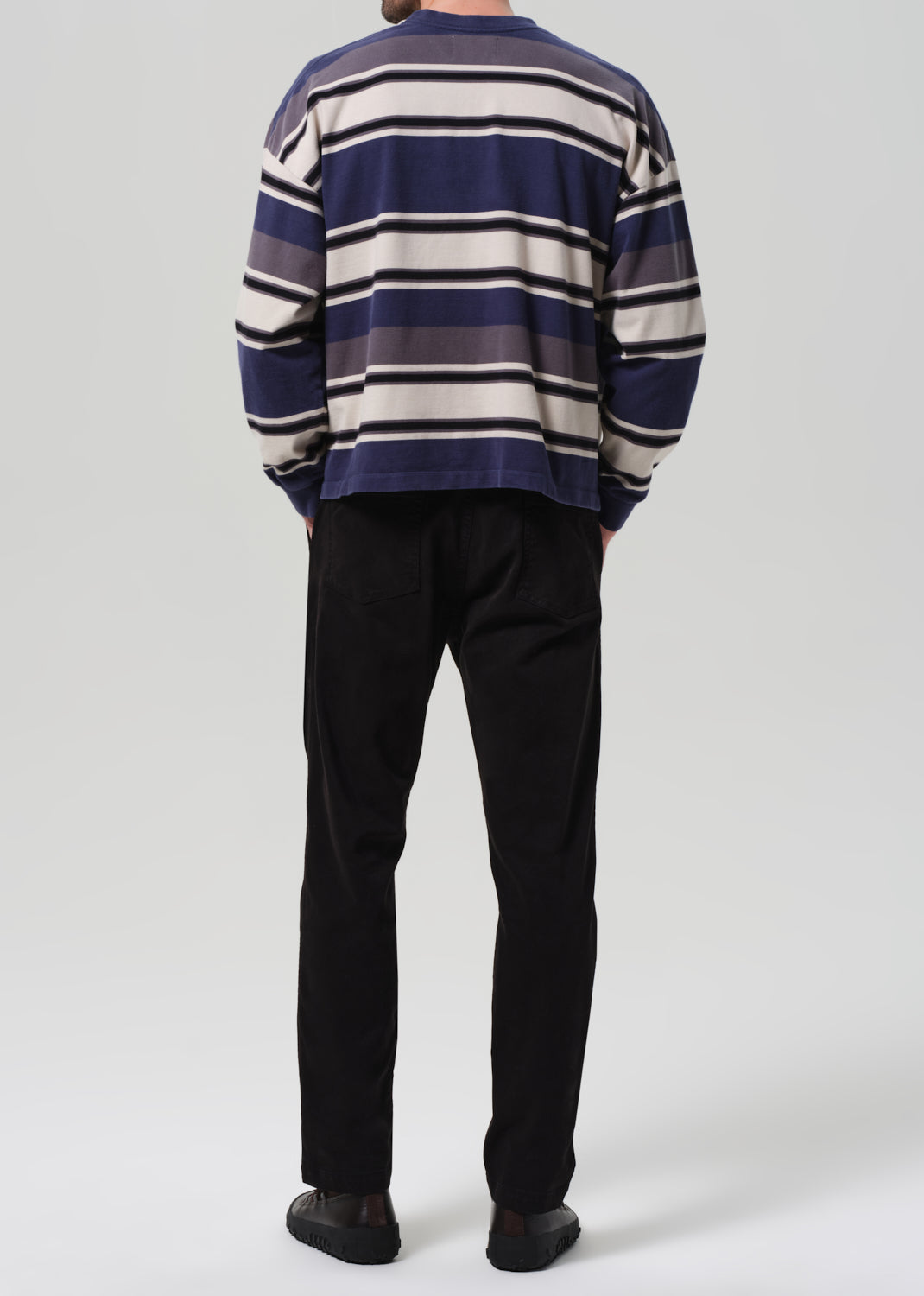 Person wearing a striped sweater and black pants on a plain background