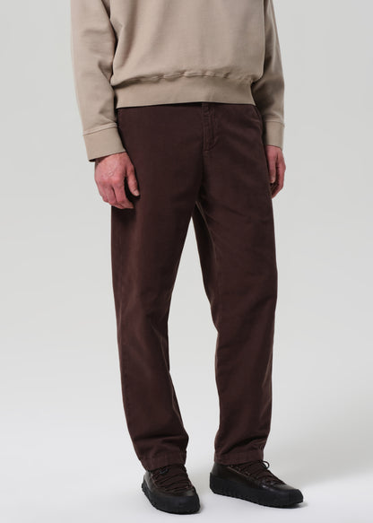 Person wearing brown pants and beige sweatshirt on a plain background