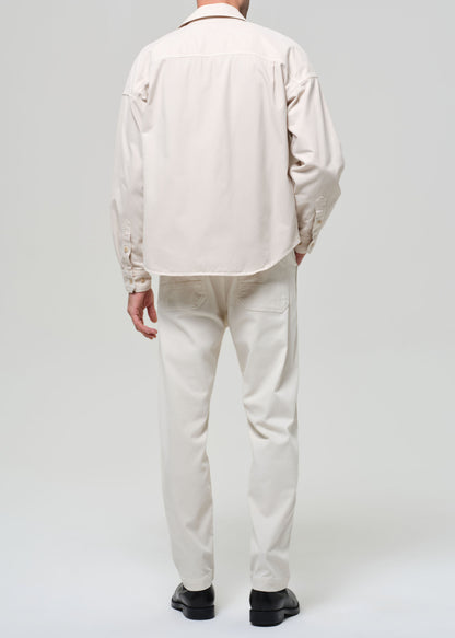 Person wearing a beige shirt and pants on a white background