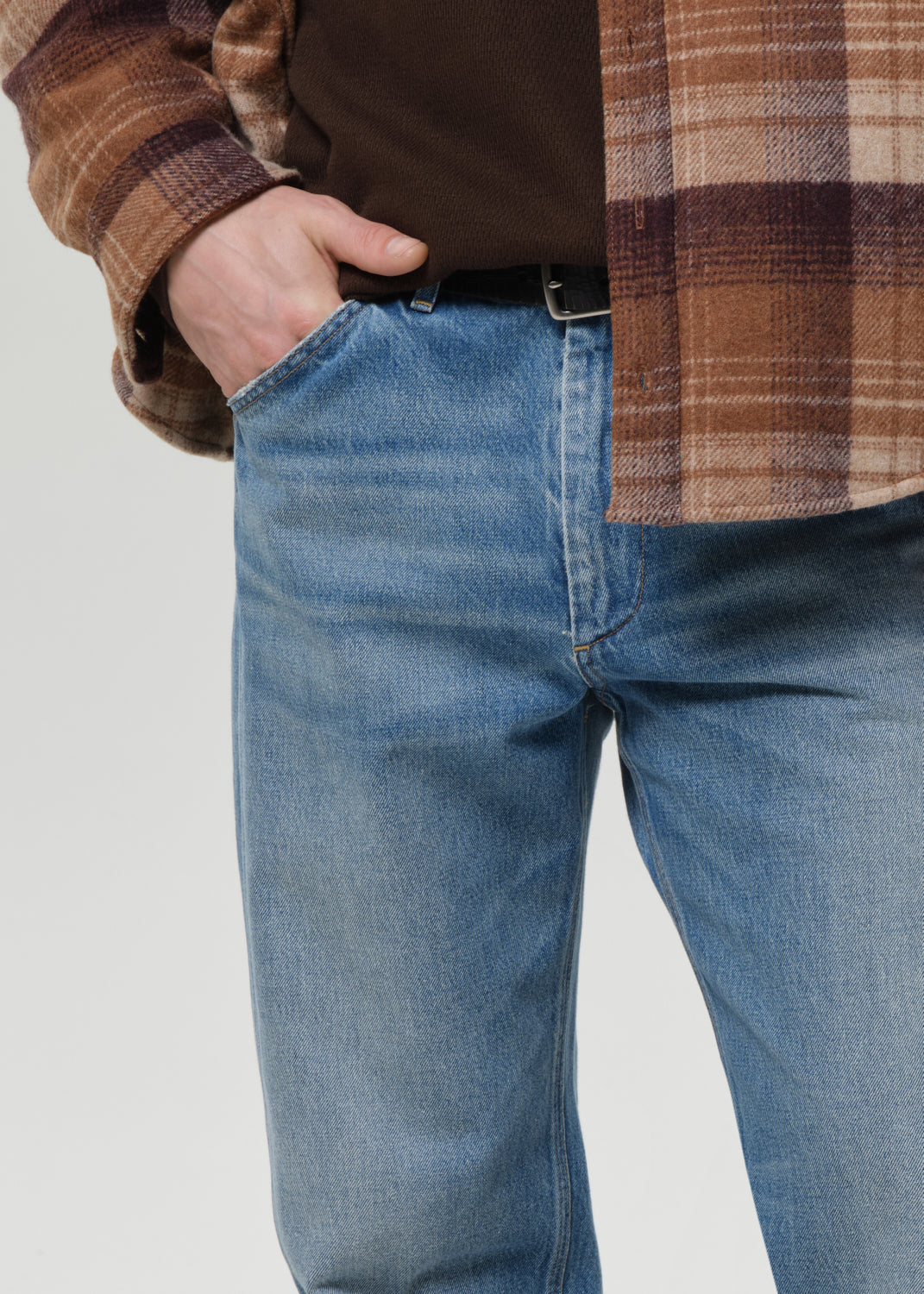 Close-up of light blue straight leg jeans on a grey background.