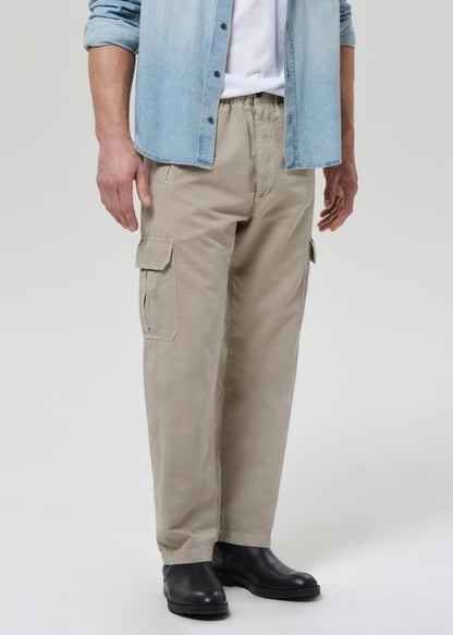 Person wearing beige cargo pants with a denim shirt on a plain background