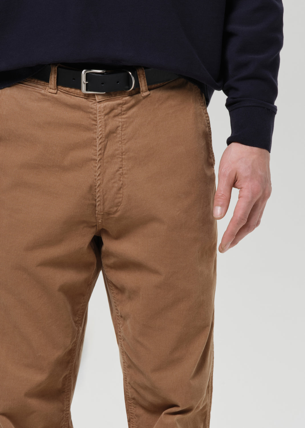 Brown pants worn by a person on a grey background