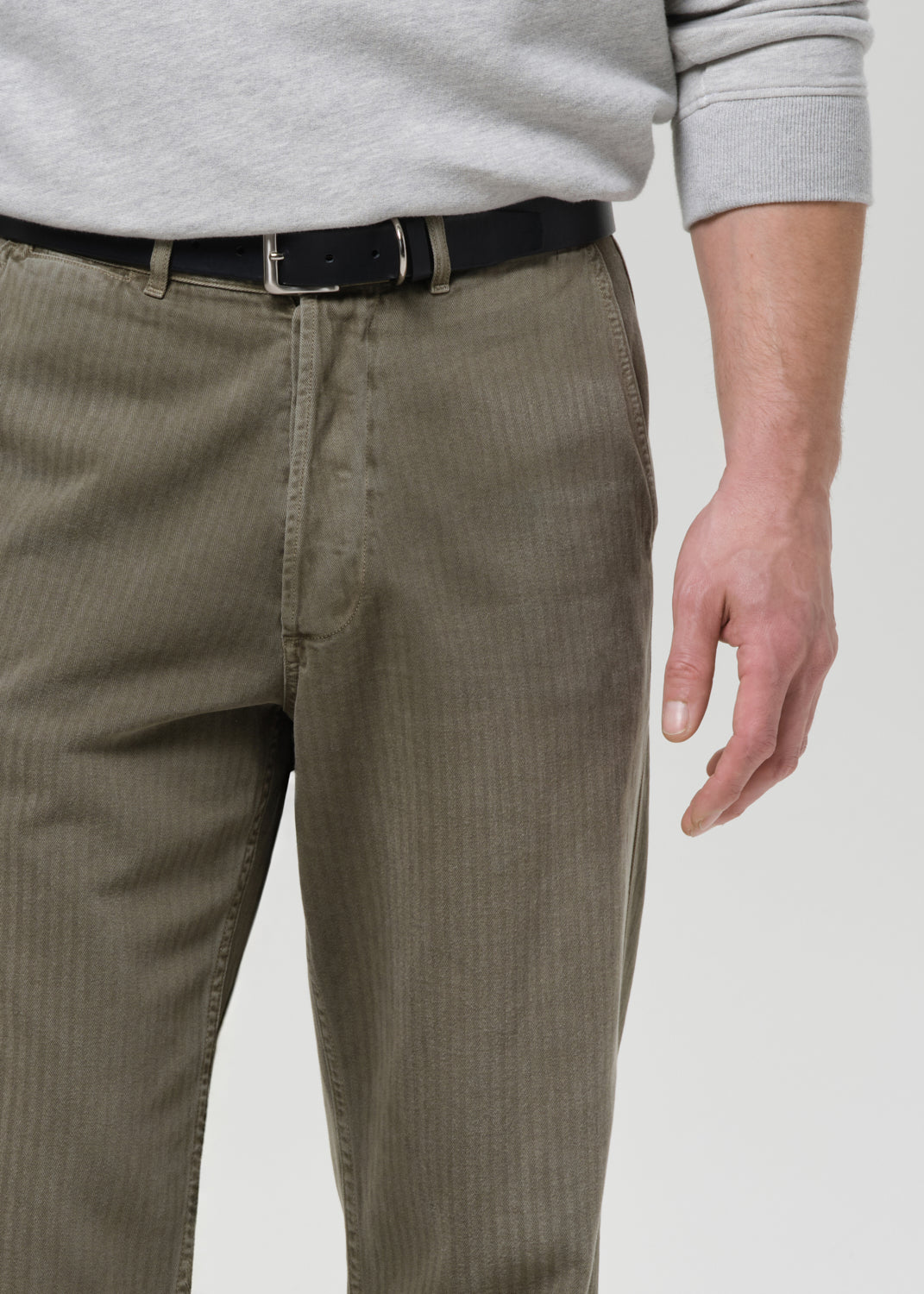 Person wearing brown pants with a gray sweater on a grey background