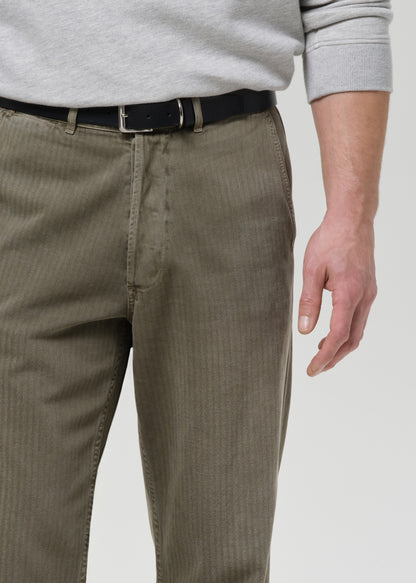 Person wearing brown pants with a gray sweater on a grey background