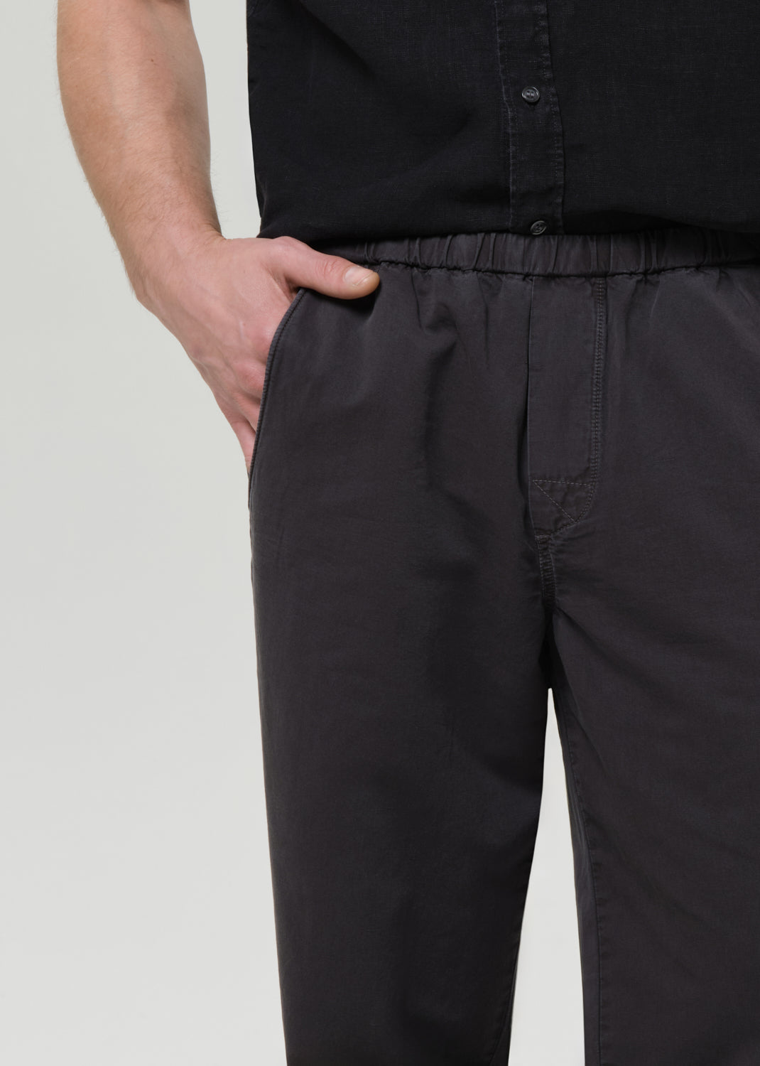 Man wearing a black button-up shirt and pants on a plain background