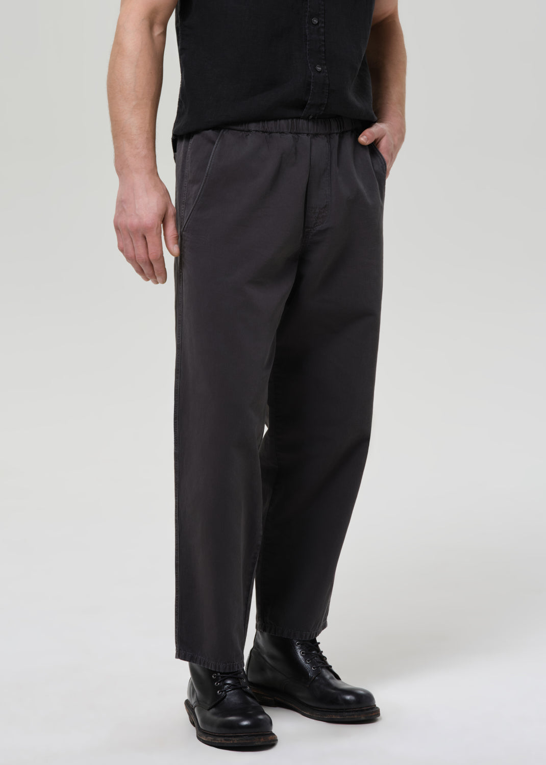 Man wearing a black button-up shirt and pants on a plain background