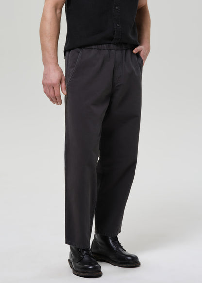Man wearing a black button-up shirt and pants on a plain background