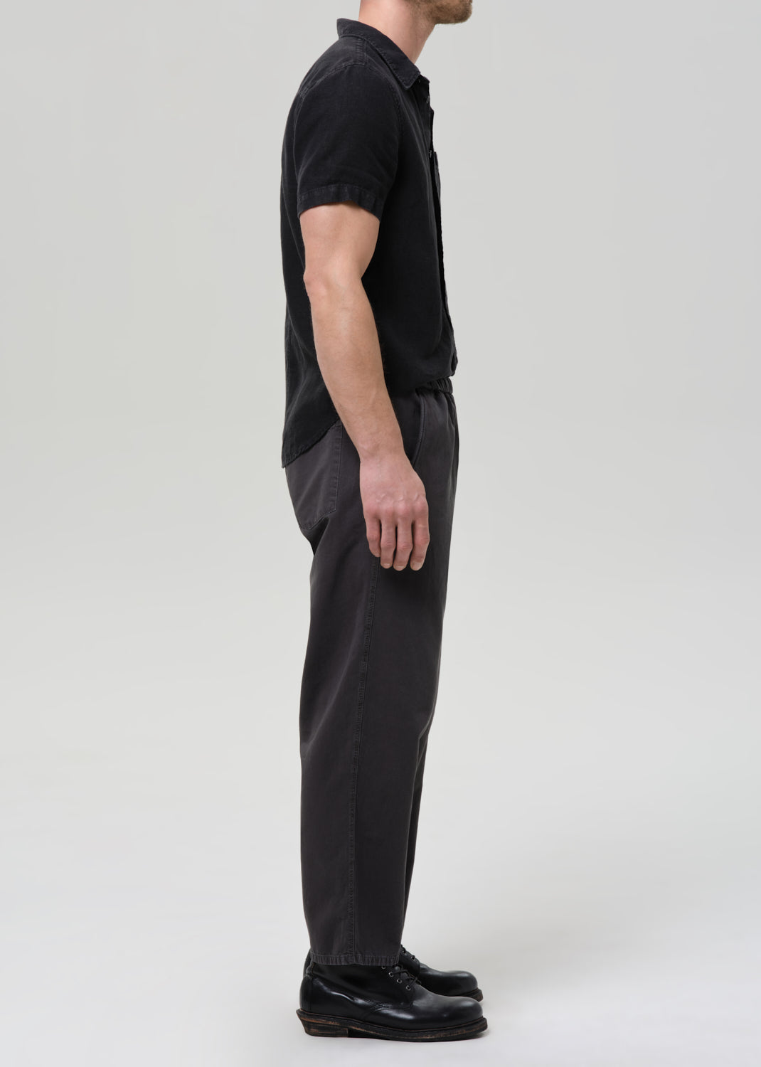 Man wearing a black button-up shirt and pants on a plain background